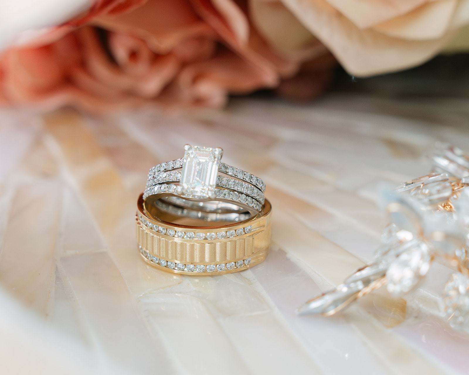 Wedding bands and engagement ring in front of bouquet