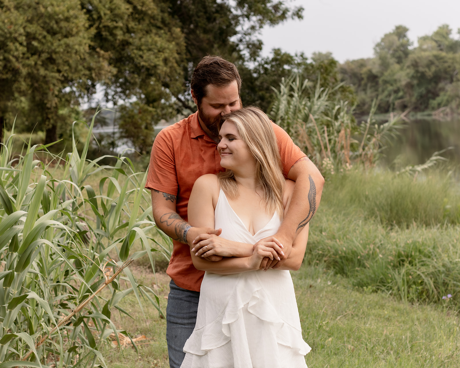 Couple hugging near river during an outdoor engagement session in Waco