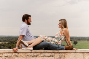 Engaged couple sitting on ledge during outdoor photoshoot