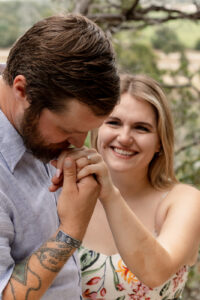 Groom to be kissing fiance's hand during outdoor engagement session