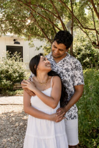 Couple smiling at each other in garden at Magnolia for engagement photos