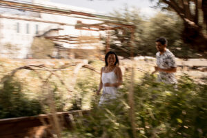 Motion blur photo of engaged couple running through garden