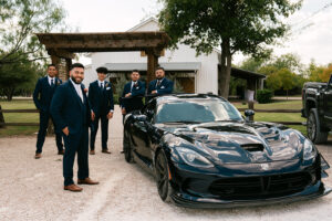 Groom and groomsmen with car in front of venue