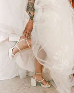 Bride fixing heels in wedding dress