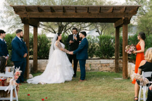 Bride and groom holding hands at outdoor wedding ceremony