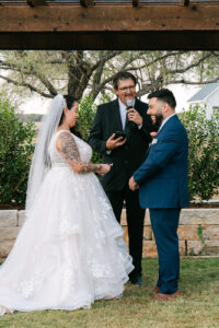 Bride and groom exchanging rings at outdoor wedding ceremony