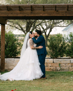 Bride and groom first kiss at outdoor wedding ceremony