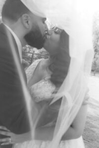 Bride and groom kissing under the veil during bridal portraits