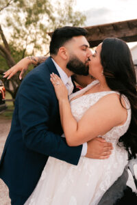 Bride and groom kissing against car in front of Waco venue