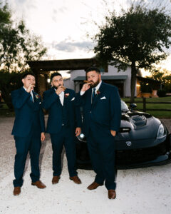 Groomsmen with cigars in front of car at wedding