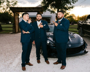 Groomsmen with cigars in front of car at wedding