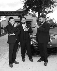 Groomsmen with cigars in front of car at wedding