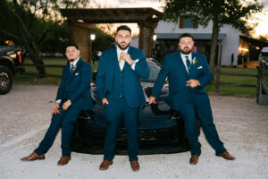 Groomsmen with cigars in front of car at wedding