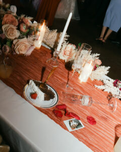 Cake, champagne flutes, and bouquet on head table at wedding reception