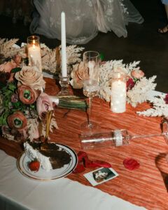 Cake, champagne flutes, and bouquet on head table at wedding reception