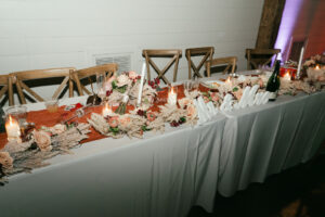 Cake, champagne flutes, and bouquet on head table at wedding reception