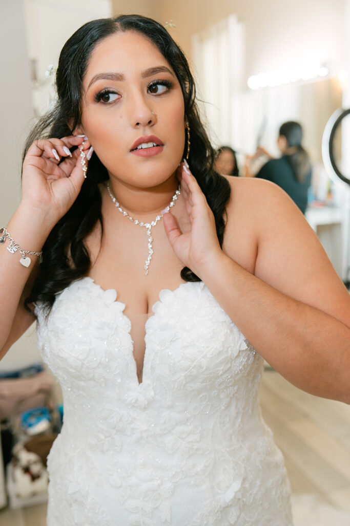 Bride putting on jewelry in bridal suite