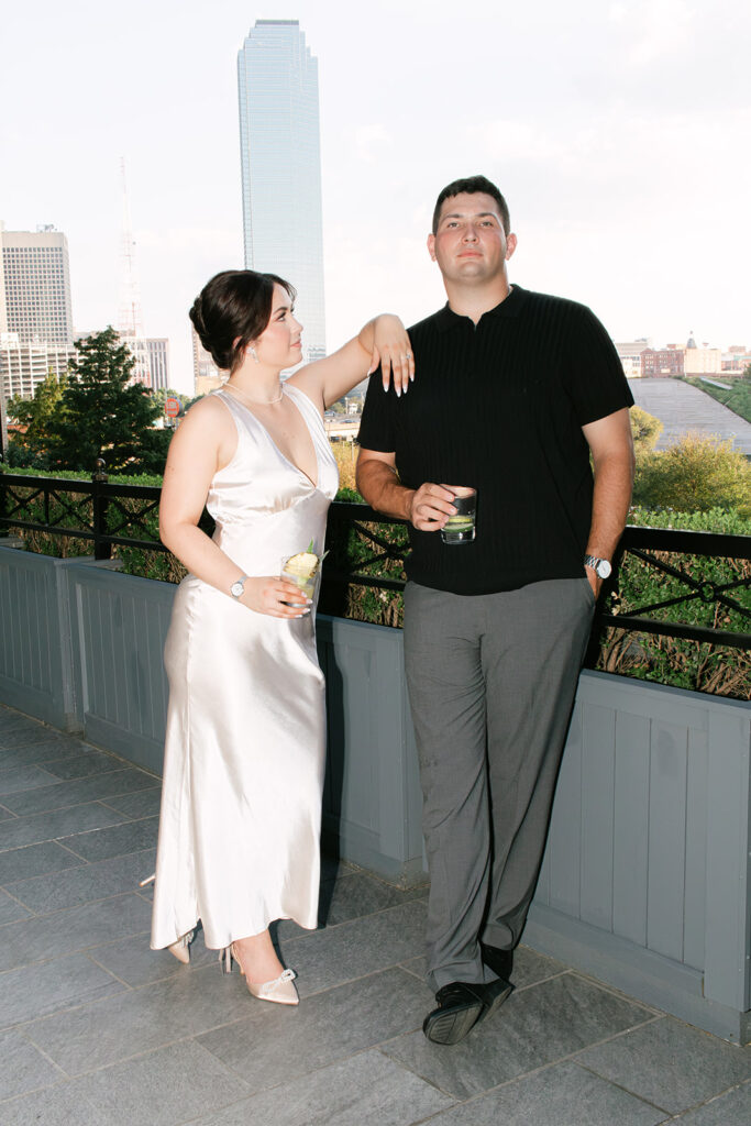 Couple poses at bar with skyline for engagement photos