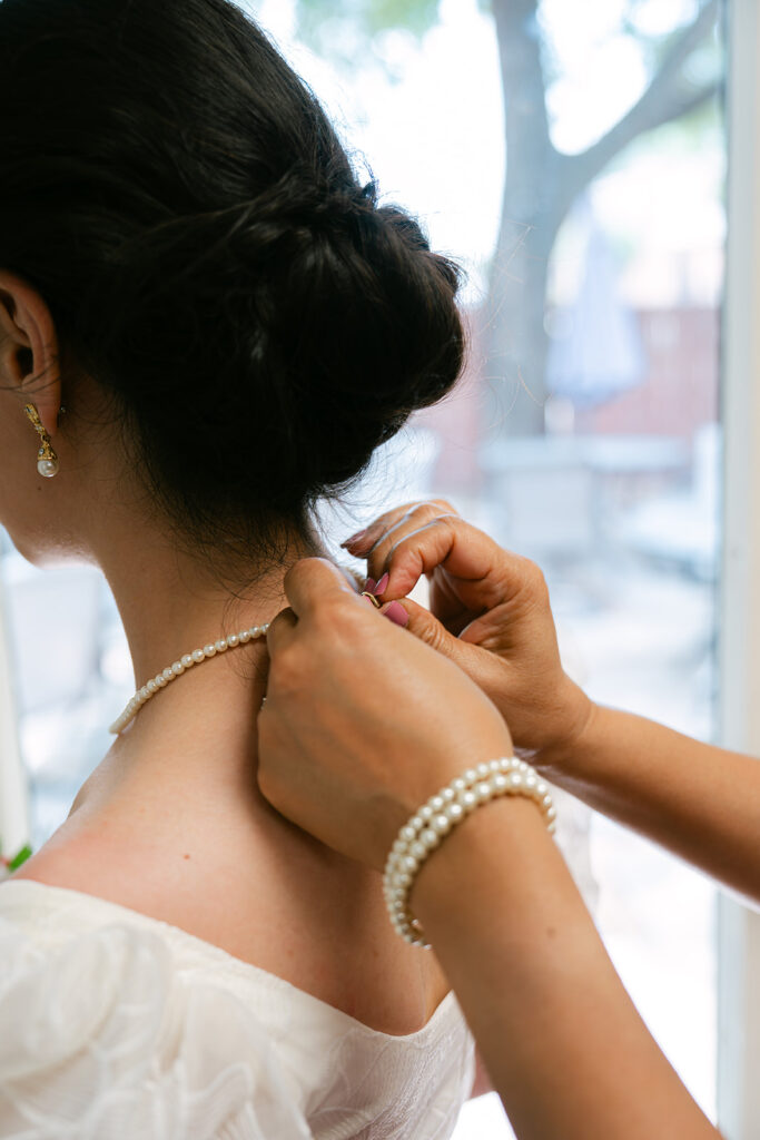 Getting ready photo of mother of bride putting on jewelry