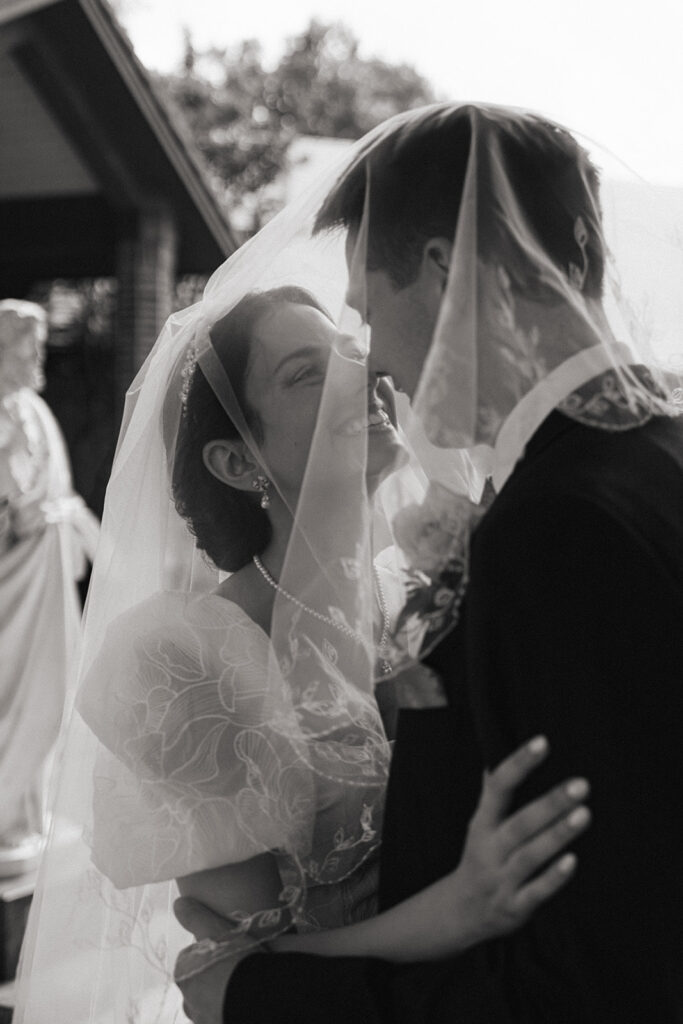 Bride and groom under the veil during bridal portraits after Catholic wedding
