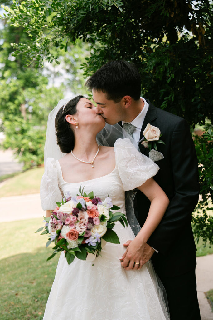 Bride and groom kissing during bridal portraits after Catholic wedding