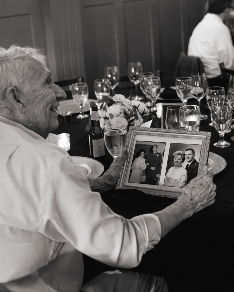 Guest smiling at old wedding photo table decor at reception