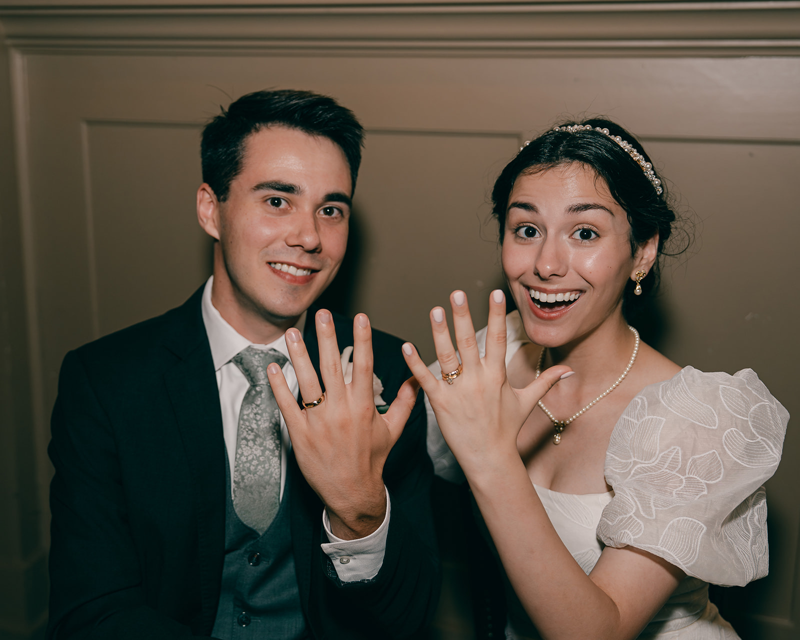 Bride and groom show off rings at wedding reception