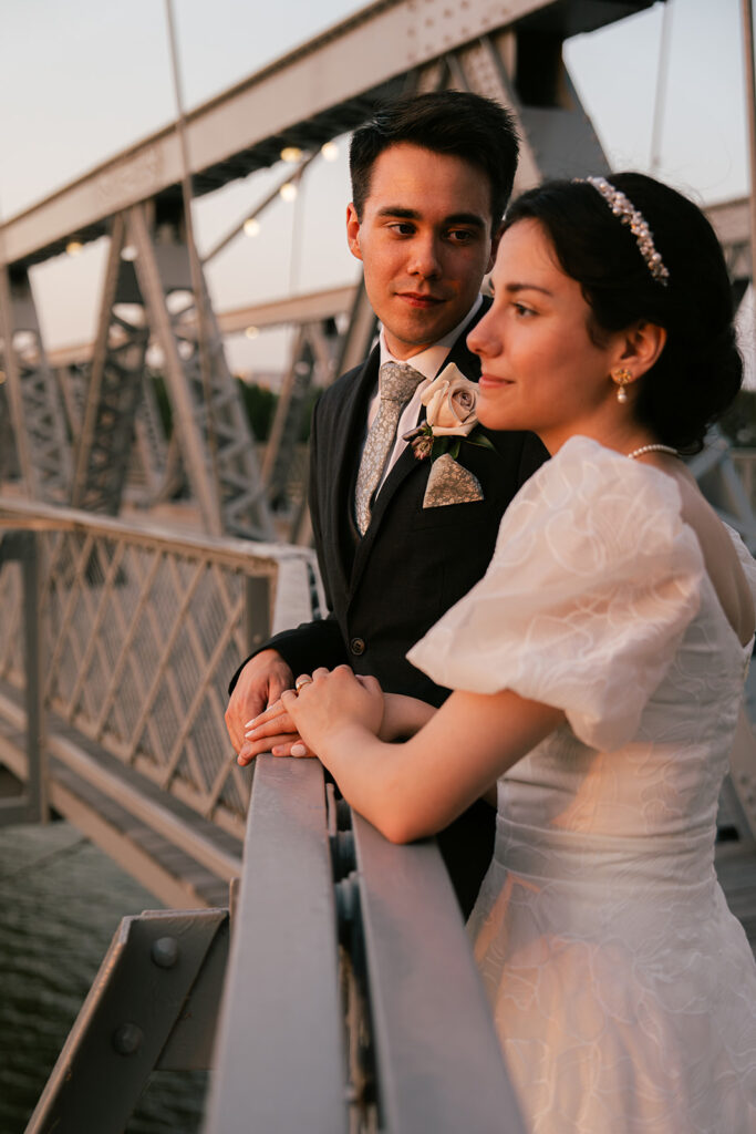 Bride and groom at suspension bridge during sunset bridal portraits after wedding